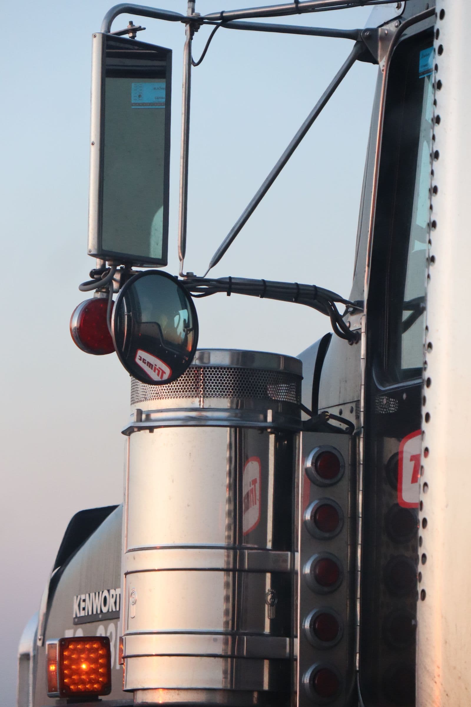 Close-up of a semi-truck cab with chrome exhaust stack, mirror, and marker lights